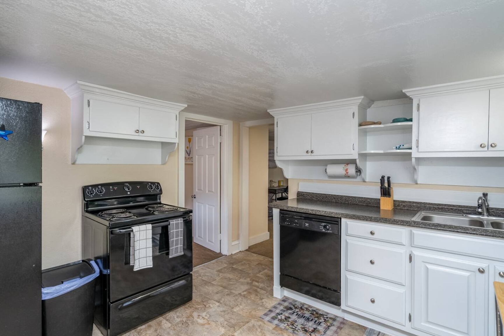 Kitchen with black appliances, white cabinets, and granite countertops.